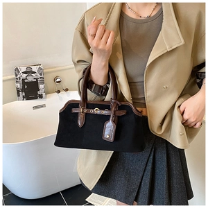 Gros plan du sac à main vintage en daim noir avec poignées en cuir marron et métal