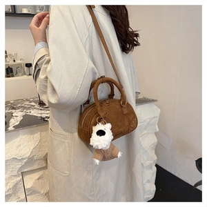 Close-up of brown suede bowling bag with metal studs and cute plush puppy charm