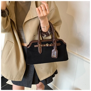 Détail du sac en daim noir mat avec lanières en cuir marron et boucle dorée