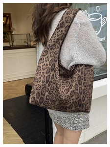 Close-up of leopard print canvas tote bag carried by a model in a casual street setting