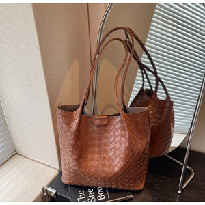 Detailed view of caramel woven leather tote bag with magnetic clasp and braided texture