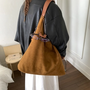 Dettaglio della grande borsa tote in pelle scamosciata marrone con texture minimalista e manico