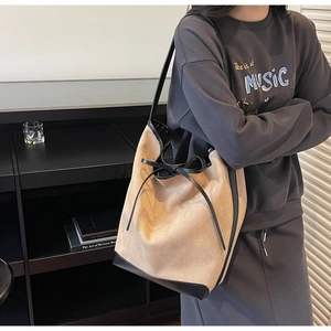 Gros plan du sac cabas en daim beige avec bordures en cuir noir et détail de nœud