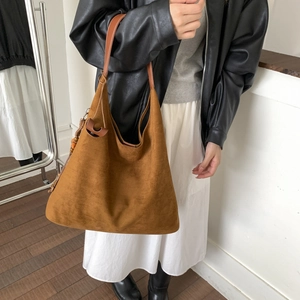 Dettaglio della grande borsa tote in pelle scamosciata marrone con nappa di legno