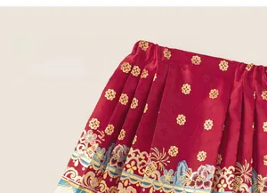 Close-up of red satin Mamian skirt featuring golden floral embroidery and pleated texture