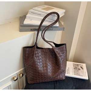 Close-up of deep brown woven leather texture on a spacious tote bag with soft lighting