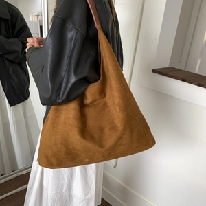 Vista laterale della borsa tote oversize in pelle scamosciata marrone indossata da modella