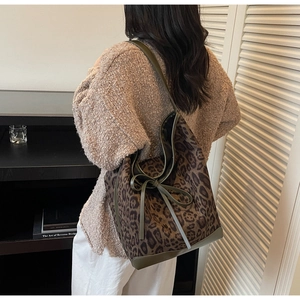 Détail du sac hobo léopard avec garniture en cuir olive et nœud porté par un mannequin