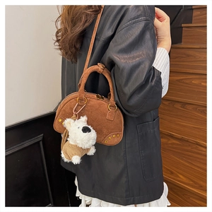 Close-up of brown suede bowling bag with a cute plush puppy pendant and gold hardware