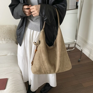 Dettaglio della borsa hobo in pelle scamosciata marrone con nappa di perline di legno