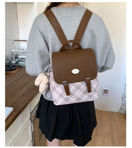 Close-up of pink plaid backpack with brown leather flap and cute rabbit charm detail