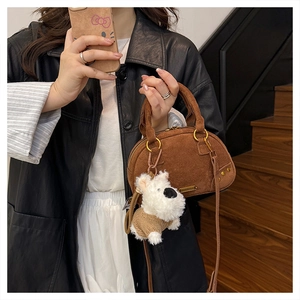 Detail of vintage brown suede bowling bag featuring gold rings and cute plush charm