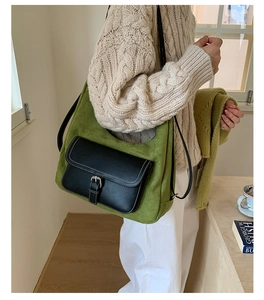 Detail of green suede crossbody bag with black leather pocket and silver metal buckle