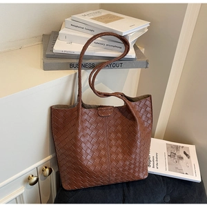 Detailed view of dark brown woven leather tote bag with elegant texture and long straps