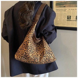 Detail einer großen Shopper Tasche mit Leopardenmuster und braunen Lederriemen am Model