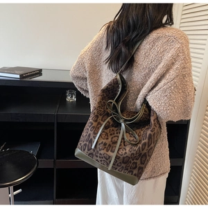 Détail du sac cabas léopard avec bordures en cuir vert et nœud décoratif élégant