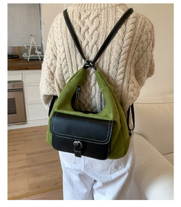 Detail of green suede backpack featuring black leather flap and silver metal buckle