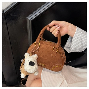 Detail showing vintage brown suede bowling bag with golden hardware and plush dog charm