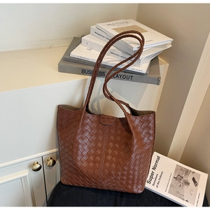 Close-up of brown woven texture and long shoulder straps on a casual tote bag