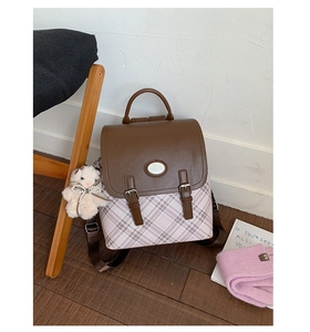 Close-up of vintage plaid backpack featuring brown leather flap and bear keychain