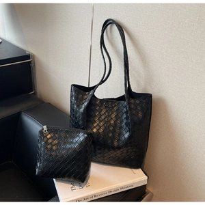 Detail of black woven texture tote bag and matching inner pouch on a sofa