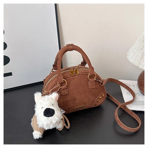 Detailed macro of brown suede bowling bag featuring golden hardware and plush puppy charm
