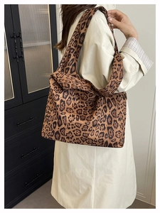 Detail of the leopard print tote bag styled with a beige trench coat on shoulder
