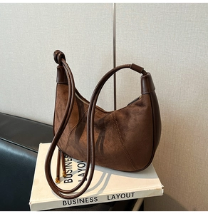 Detail of dark brown faux suede dumpling bag with zipper closure and thin leather strap