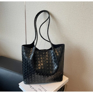 Detail of black woven leather tote bag with large checkered pattern on book prop