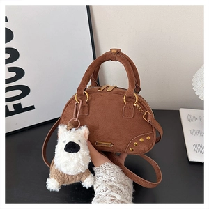 Detail of brown suede handbag with golden hardware and white plush puppy charm