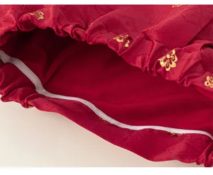 Detail of red satin fabric with golden floral patterns and precise stitching on the sleeve cuff