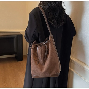 Détail du sac cabas en daim marron avec nceud en cuir et coutures renforcées de qualité
