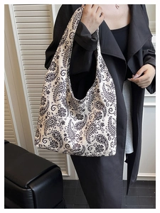 Detail showing the large canvas tote bag with black paisley print on a white surface