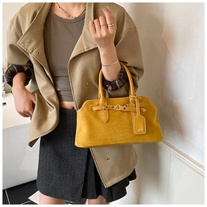 Détail du sac à main jaune en cuir givré avec boucle vintage et étiquette décorative