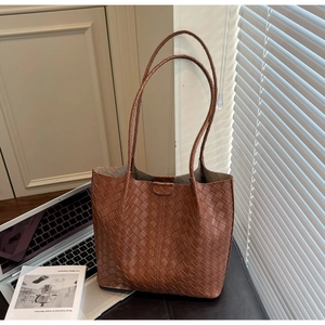 Detailed close-up of brown woven leather tote bag with fine texture and slim straps
