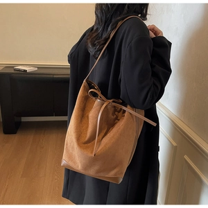 Sac fourre-tout en daim marron avec nœud décoratif porté par un mannequin femme