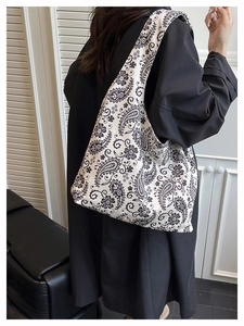Detail of large canvas tote bag with black paisley patterns shown on female model