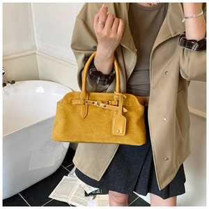 Gros plan d'un sac à main rétro en daim jaune avec lanières en cuir et accents métal