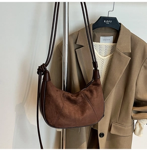 Detail of a brown suede crescent bag with smooth leather trim and knotted strap detail