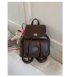 Detail eines kaffeebraunen Vintage-Lederrucksacks mit silbernen Drehverschlüssen auf Bank