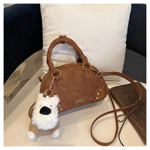 Detailed close-up of dark brown suede vintage handbag with silver studs and plush charm