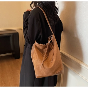 Gros plan du sac cabas en daim marron avec poignées en cuir et détails de cordon