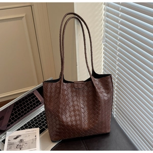 Detail of deep brown woven tote bag with Intrecciato texture and slim shoulder straps