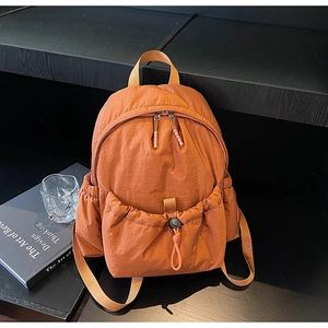 Detail of orange nylon backpack with drawstring pocket and smooth crinkled texture