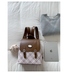 Detail of vintage college-style backpack with brown faux leather flap and plaid pattern