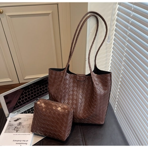 Close-up of dark brown woven leather tote with matching small zip pouch on a desk