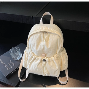 Detailed view of the drawstring front pocket and textured nylon fabric on the beige backpack