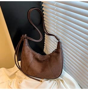 Detailed view of dark brown suede hobo bag with diagonal stitching and knotted strap