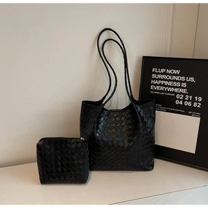 Detailed view of black woven leather tote set with matching zipper pouch on marble surface