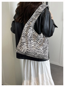 Detail of the large zebra print tote bag shown from behind on a model shoulder